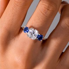 a woman's hand with a diamond and blue sapphire engagement ring on her finger