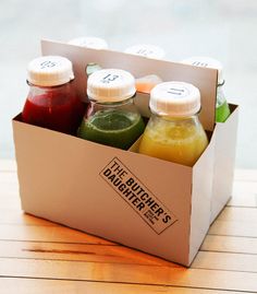 six bottles of juice in a box on a table