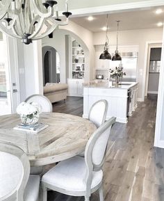 a dining room table and chairs in front of a kitchen with an open floor plan