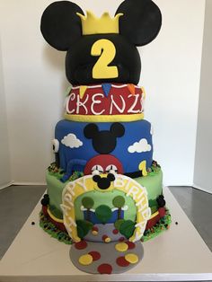 a three tiered cake decorated with mickey mouse and other characters, including the number two