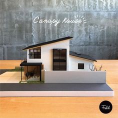 a model of a house sitting on top of a table next to a gray wall