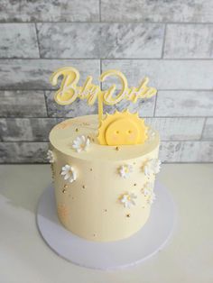 a white cake with yellow frosting and a smiley face on top that says baby due