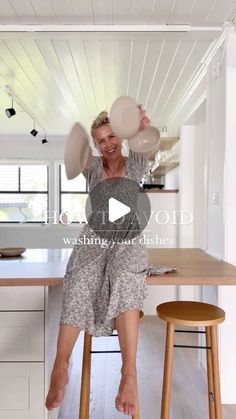 a woman sitting on top of a stool holding a frisbee over her head