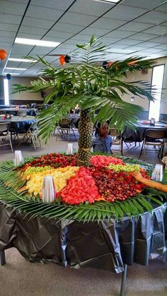 an arrangement of fruit is displayed in the middle of a room with tables and chairs