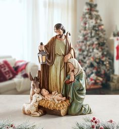 a nativity scene with figurines in front of a christmas tree