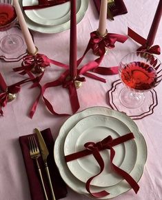 the table is set with plates, silverware and red ribbons on it's edge