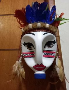 a white mask with feathers on it's head sitting on top of a wooden floor