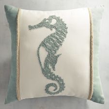 a seahorse embroidered on a white and green pillow