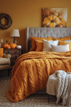 a bed with orange blankets and white pillows in a yellow room next to a chair