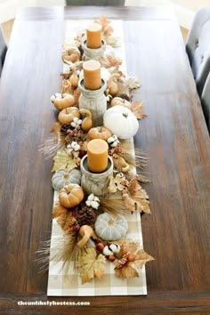 a long table with candles and pumpkins on it, along with other fall decorations