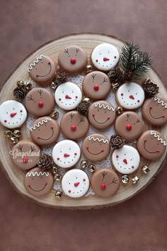 a platter filled with lots of decorated cookies on top of a wooden table next to a pine cone