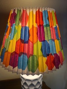 a multicolored lamp shade sitting on top of a white table next to a wall