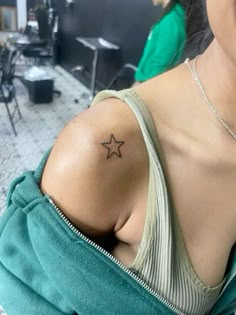 a woman with a small star tattoo on her left shoulder and right arm behind her back