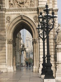 an archway in the middle of a stone building with a light pole and street lamp