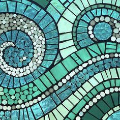 a close up view of a blue and green mosaic glass window with swirls on it