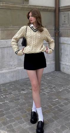 a woman in short skirt and sweater posing for the camera