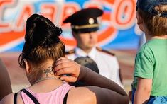 a woman with tattoos on her back is standing in front of two children and an officer