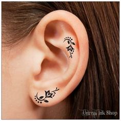 an ear tattoo with flowers and leaves in black ink on the left side of the ear