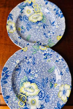 two blue and white plates sitting on top of a wooden table next to each other