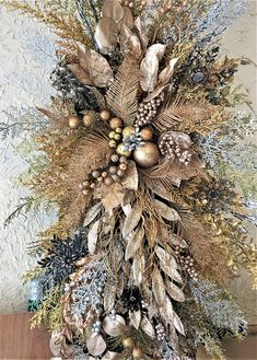 a christmas tree with gold and silver decorations on it's branches, pine cones, fircones and berries