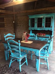 a dining room table and chairs with blue paint on the top, in front of a brick wall