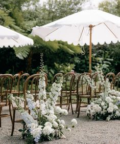 an outdoor ceremony setup with white flowers and umbrellas