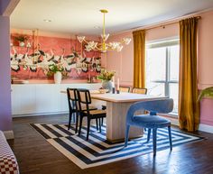 a dining room with pink walls and blue chairs