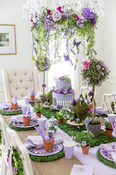 a table topped with lots of purple and green flowers next to potted planters