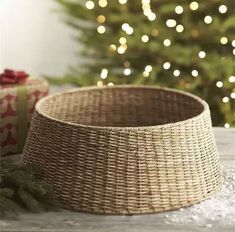 a wicker basket sitting on top of a wooden table next to a christmas tree