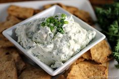 a white bowl filled with dip surrounded by tortilla chips