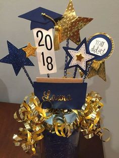 a graduation centerpiece with gold and blue streamers, stars, and congratulations sign