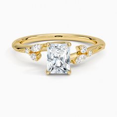 a yellow gold engagement ring with a princess cut diamond in the center and side stones