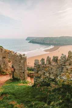 an old stone building sitting on top of a lush green field next to the ocean