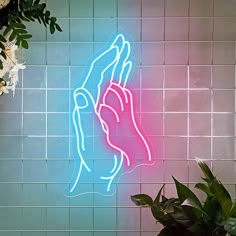 a neon sign that is on the side of a wall next to a potted plant