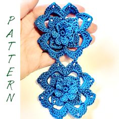 a crocheted blue flower is being held up