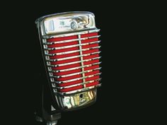 an old fashioned red and silver microphone on a black background