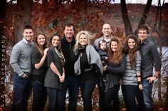 a group of people standing next to each other in front of some trees and water