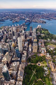 an aerial view of a city with lots of tall buildings and water in the background