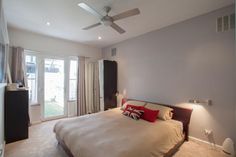 a bed room with a neatly made bed and a ceiling fan