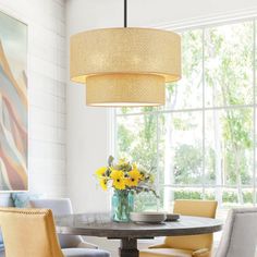 a dining room table with yellow chairs and a vase full of flowers on top of it