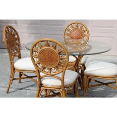 a glass table with four chairs in front of a garage door and white cushions on the floor