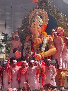 a group of men and women standing around an elephant statue in front of a crowd