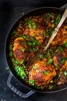 a skillet filled with chicken and lentils, garnished with parsley