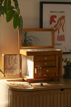 an open jewelry box sitting on top of a table next to a potted plant