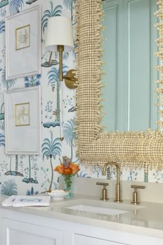 a bathroom with a mirror, sink and wallpapered walls in blue and white