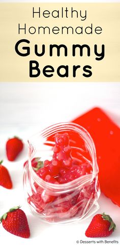 a jar filled with gummy bears next to strawberries