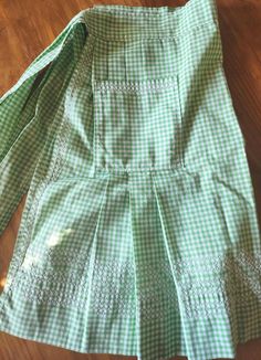 a green and white dress sitting on top of a wooden floor next to a pair of scissors