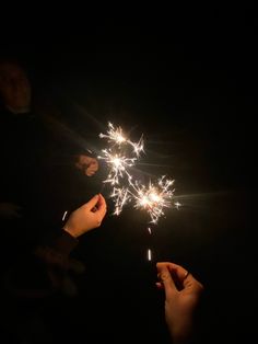 two people are holding sparklers in their hands while the other person holds them out