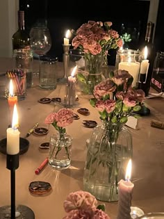 the table is set with candles and vases filled with pink flowers on top of it