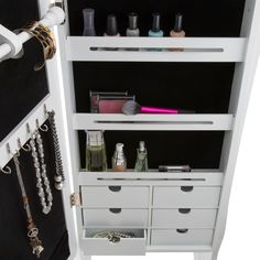 a white cabinet with drawers and jewelry hanging on the wall